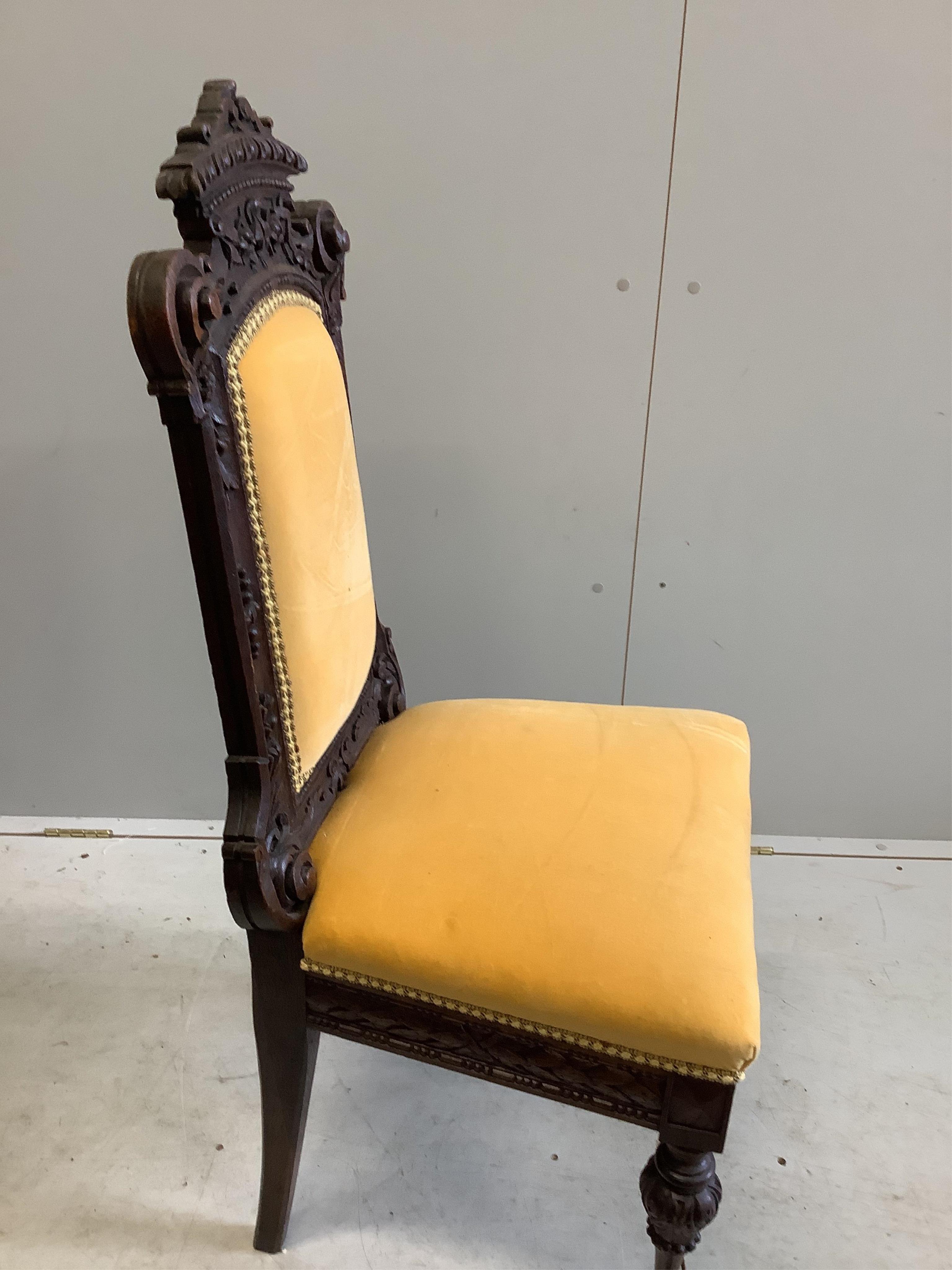 Two late 19th century Flemish carved oak dining chairs, one with arms, together with a Spanish style oak and leather elbow chair. Condition - fair to good